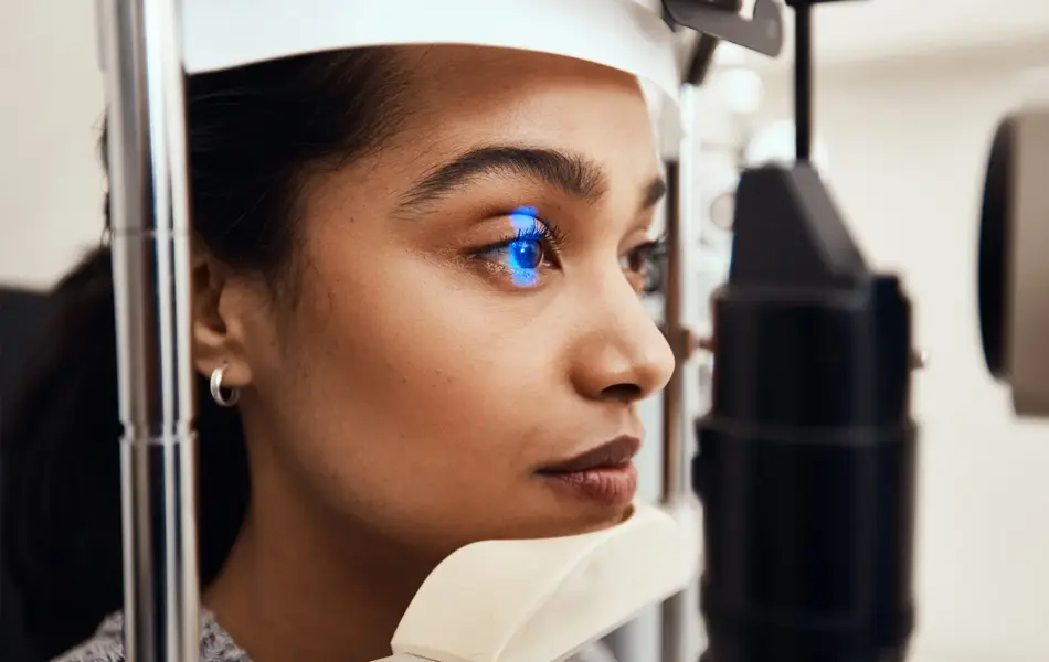 Dame som får øynene sjekket av maskin hos øyelege