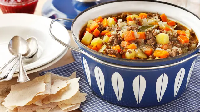 Blå gryte med elghakk, to tallerker og rødt syltetøy