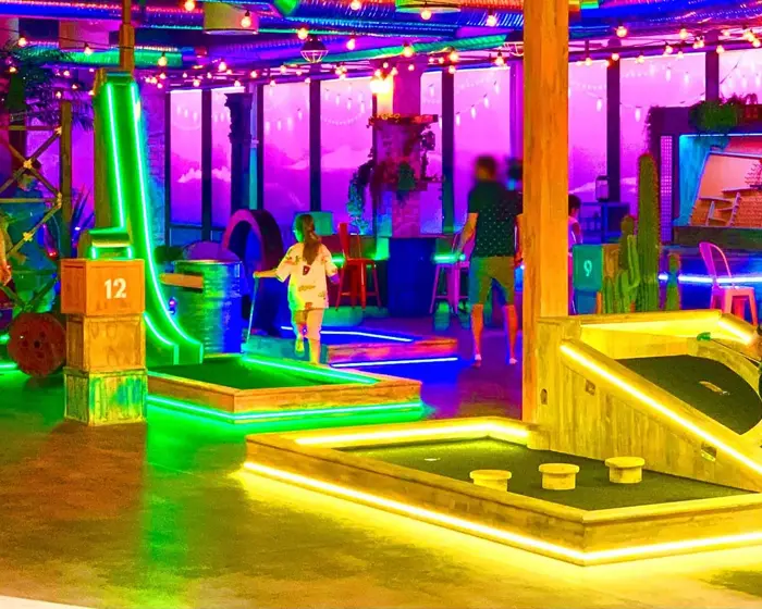 rom med masse lys og ulike golf baner med foreldre og barn som spiller