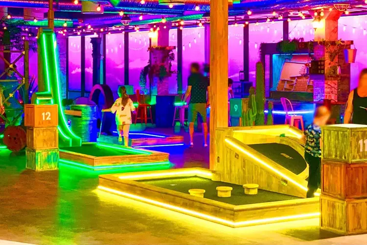 rom med masse lys og ulike golf baner med foreldre og barn som spiller