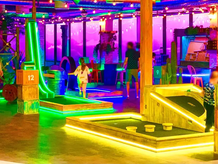 rom med masse lys og ulike golf baner med foreldre og barn som spiller