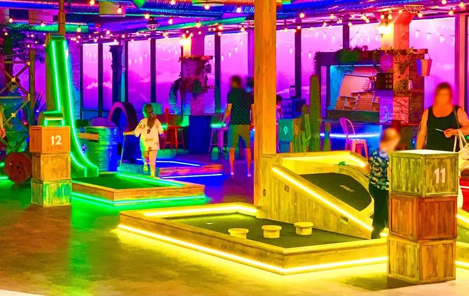 rom med masse lys og ulike golf baner med foreldre og barn som spiller