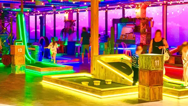 rom med masse lys og ulike golf baner med foreldre og barn som spiller