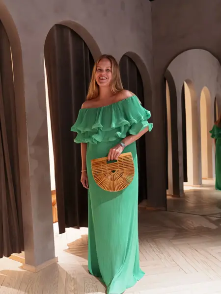 Damemodell i grønn lang kjole og stråveske