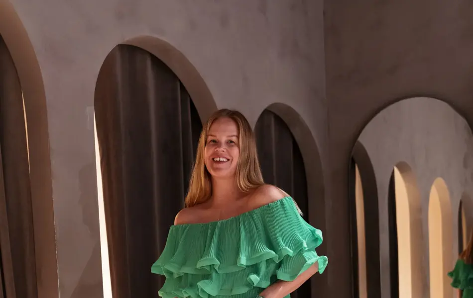 Damemodell i grønn lang kjole og stråveske