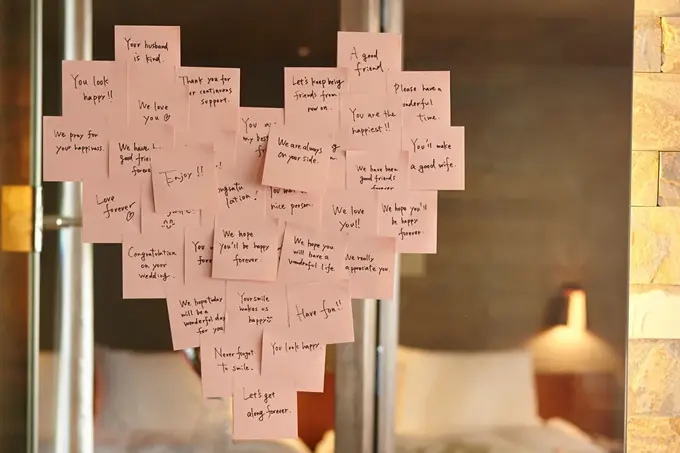 Lyserosa post-it-lapper plassert i en hjerteform på et speil