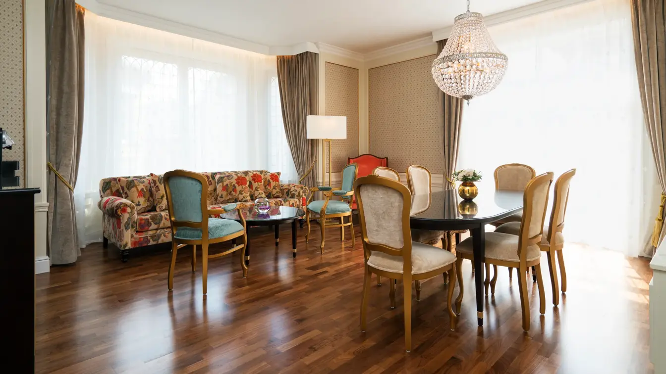 Sittegruppe med sofa og spisebord med stoler, lyskrone på suite på Hotel Bristol i Oslo sentrum