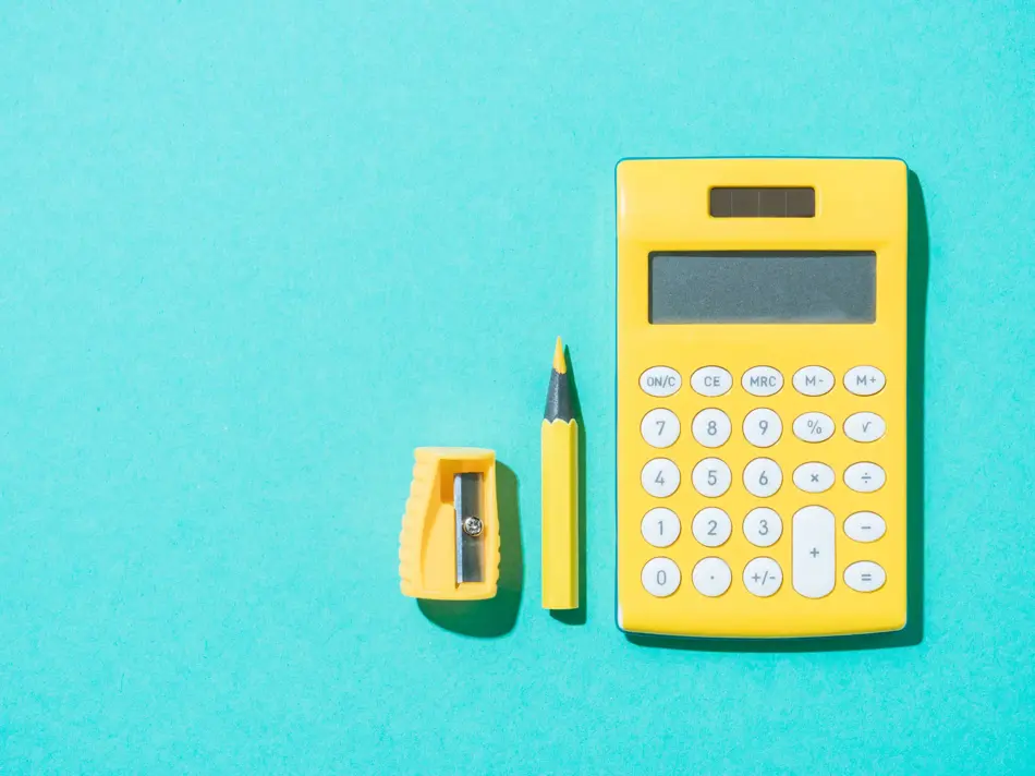 top view of arrangement of calculator, pencil and pencil sharpener on blue backdrop