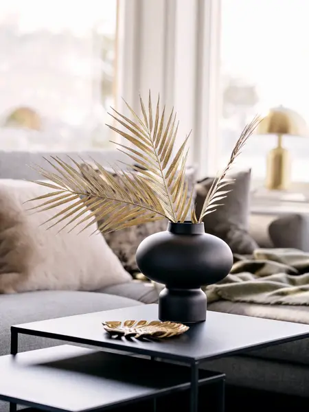 Sort firkantet bord med sort vase og beige tørkede blader