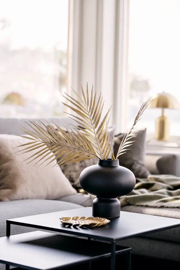 Sort firkantet bord med sort vase og beige tørkede blader