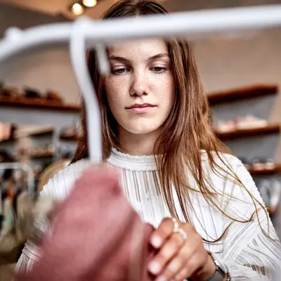 brunette kikker på klesstativ i butikk