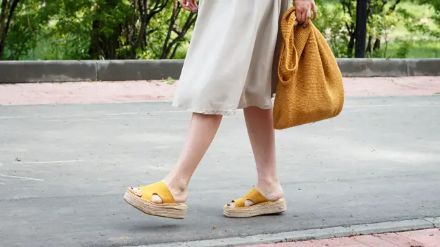 Summer fashion outfit. Girl in dress, yellow shoes and trendy knitted bag, a side view