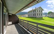Utsikt fra overbygget balkong mot hvitt herskapshus og grønne jorder, Hallingtunet i Flå.