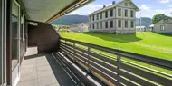 Utsikt fra overbygget balkong mot hvitt herskapshus og grønne jorder, Hallingtunet i Flå.