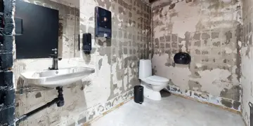 Et rustikk toalett med betongvegger