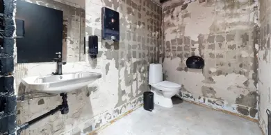 Et rustikk toalett med betongvegger