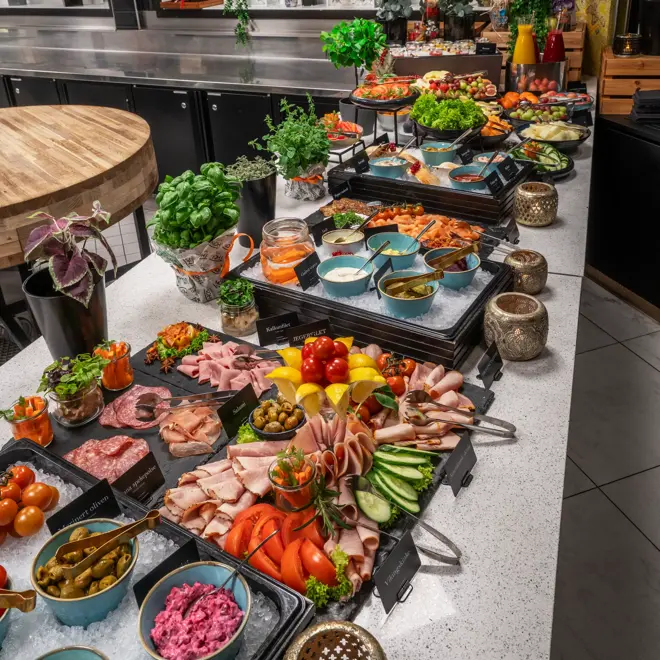 Frokostbuffet med fargerikt utvalg av pålegg, oppkuttede grønnsaker, urteplanter og frukt