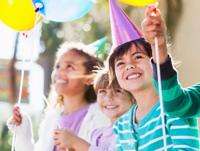 Multi-ethnic children at birthday party.  Focus on girl in foreground (4-5 years, mixed race, Hispanic / Caucasian).