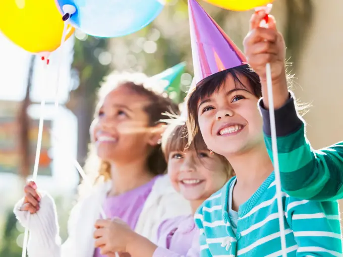 Multi-ethnic children at birthday party.  Focus on girl in foreground (4-5 years, mixed race, Hispanic / Caucasian).