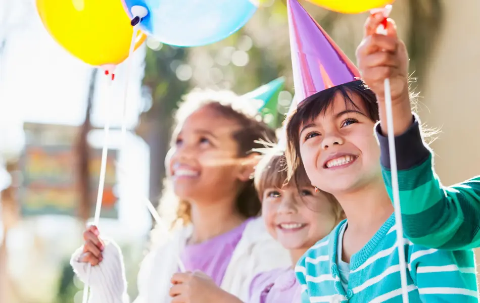 Multi-ethnic children at birthday party.  Focus on girl in foreground (4-5 years, mixed race, Hispanic / Caucasian).