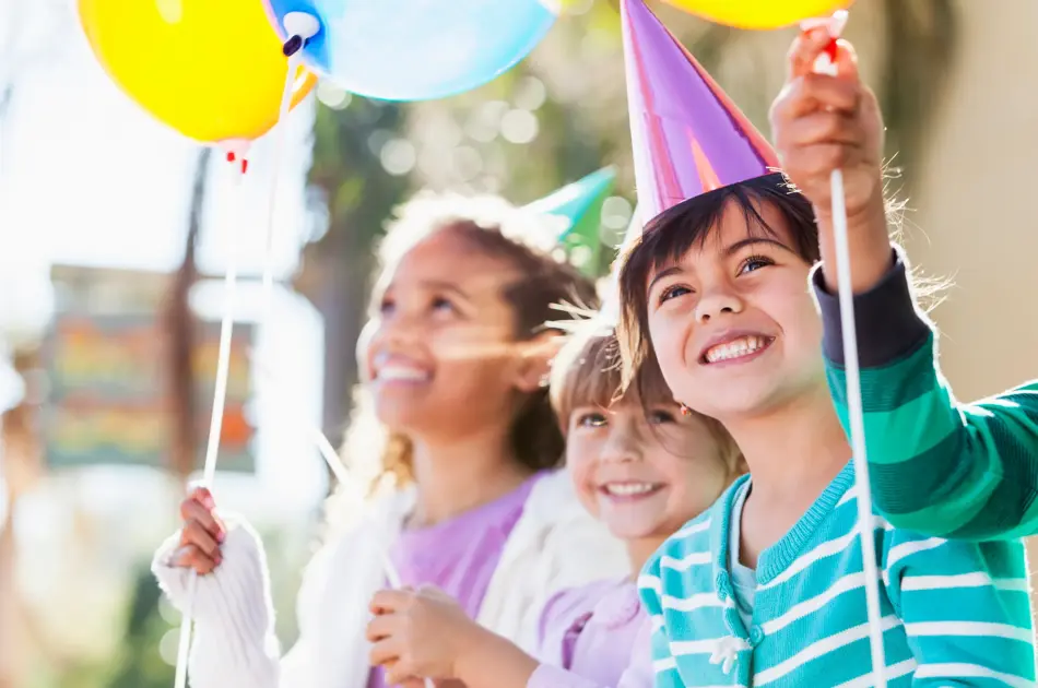 Multi-ethnic children at birthday party.  Focus on girl in foreground (4-5 years, mixed race, Hispanic / Caucasian).