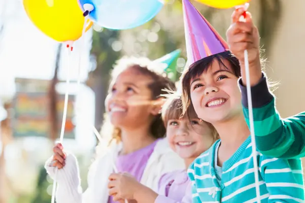 Multi-ethnic children at birthday party.  Focus on girl in foreground (4-5 years, mixed race, Hispanic / Caucasian).