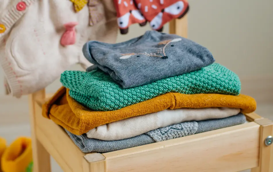 Baby organic clothes concept. Organic cotton clothing on the kids chair in children room. Selective focus.