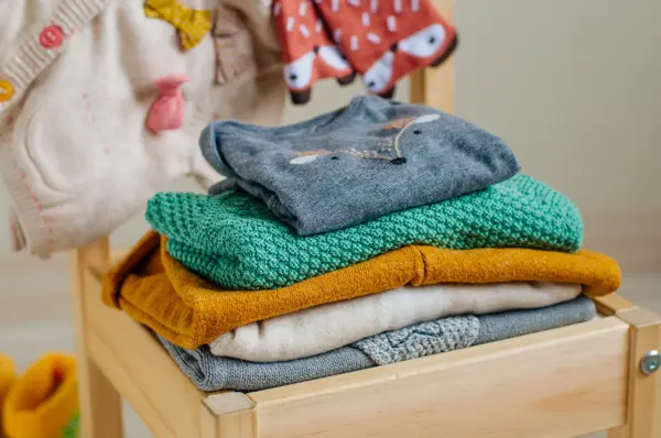 Baby organic clothes concept. Organic cotton clothing on the kids chair in children room. Selective focus.