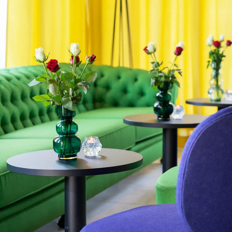blomsterdekorasjon på bordet i lobby med grønn sofa og gule gardiner på Thon Hotel Alta