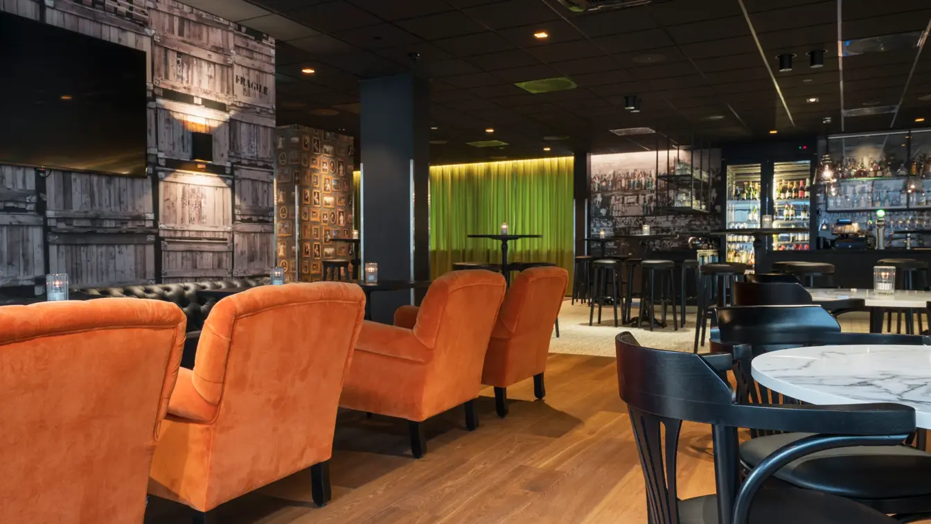 Store orange lenestoler og enkle spisebord  på Thon Hotel Oslo Airport ved Gardermoen