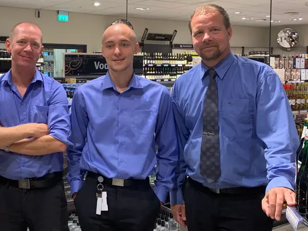 tre mannlige ansatte hos vinmonopolet