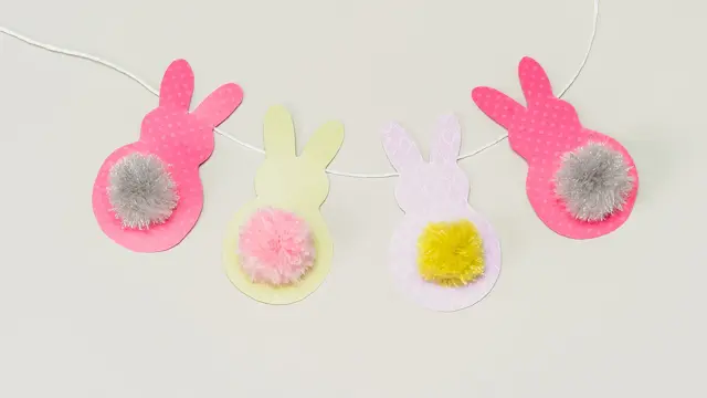 Fire påskeharer klippet i papir på en hvit snor