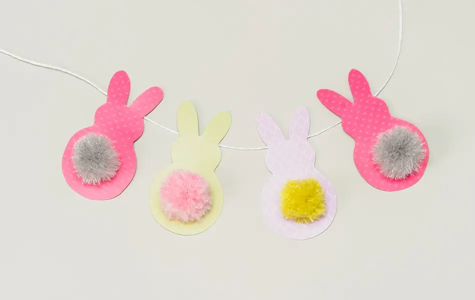Fire påskeharer klippet i papir på en hvit snor