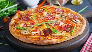 Fresh Italian pizza with chicken fillet, mushrooms, ham, salami, tomatoes, cheese on a black background. Italian food.