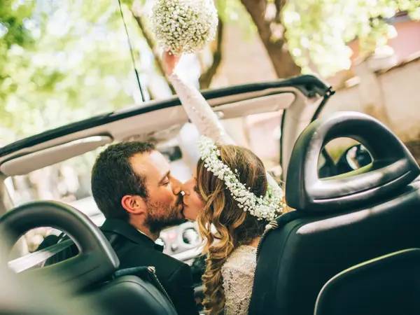 Photo of just married couple. They are kissing in the car.