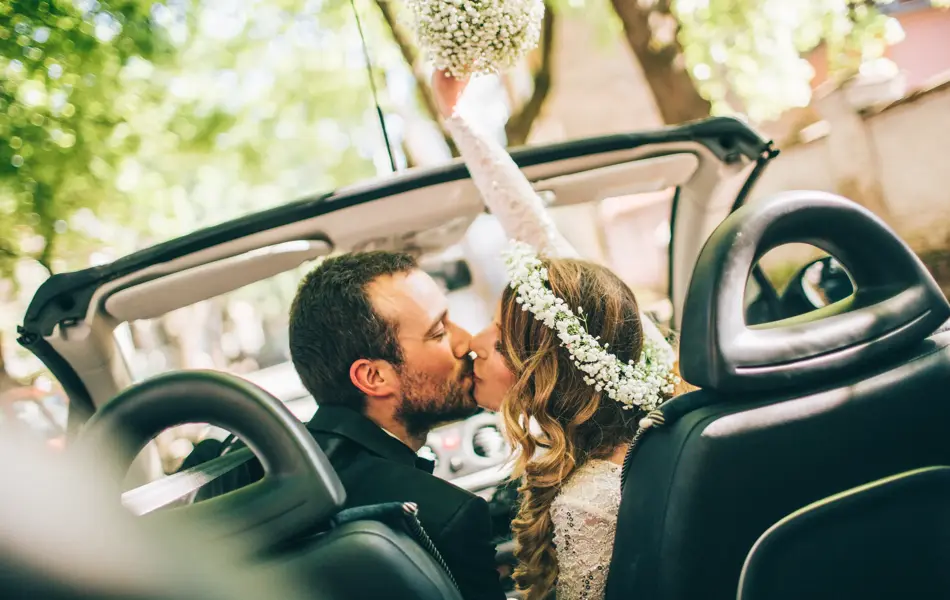 Photo of just married couple. They are kissing in the car.