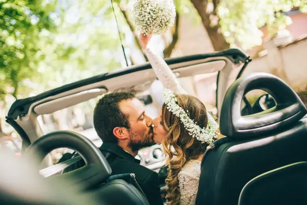 Photo of just married couple. They are kissing in the car.