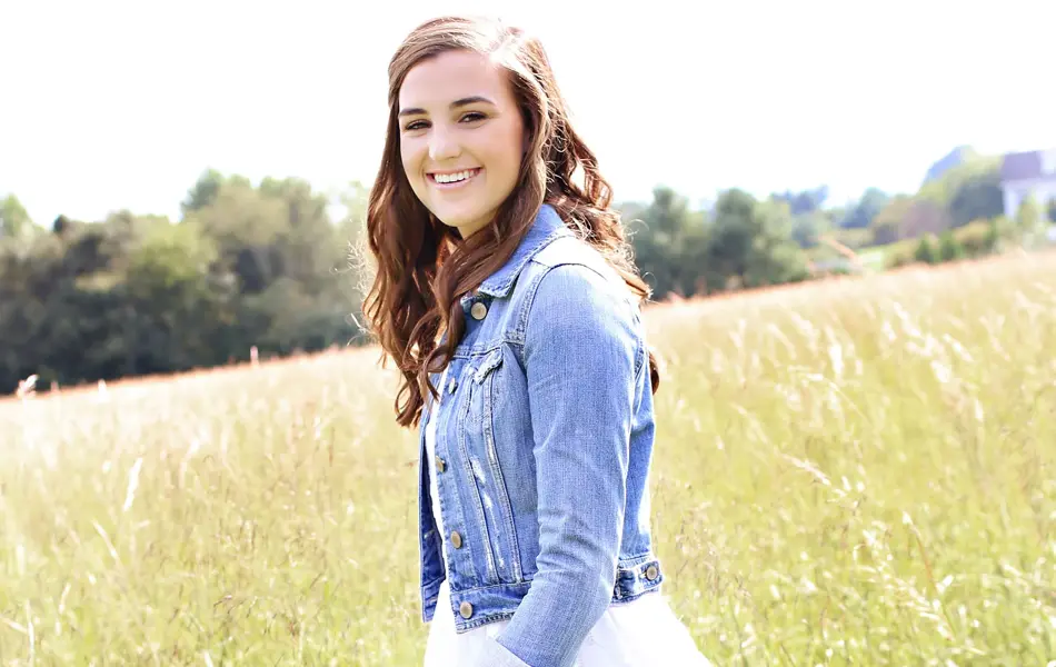 Dame med cowboyboots, sommerkjole og denimjakke går på en gresslette