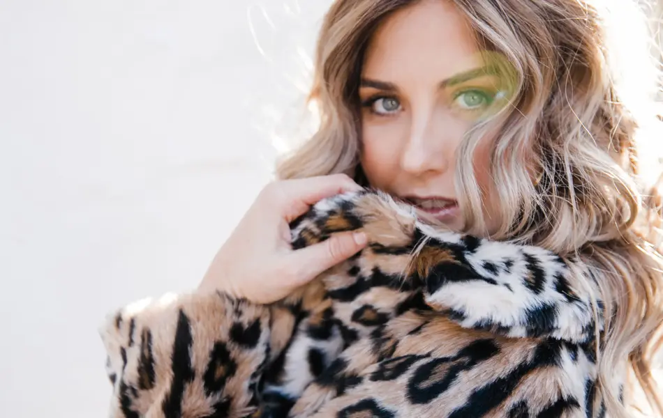 Kvinne som har på leopard fuskepels, ser inn i kamera