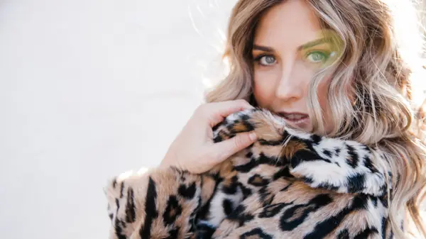 Kvinne som har på leopard fuskepels, ser inn i kamera
