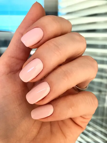 Nærbilde av hånd med pastellrosa neglelakk