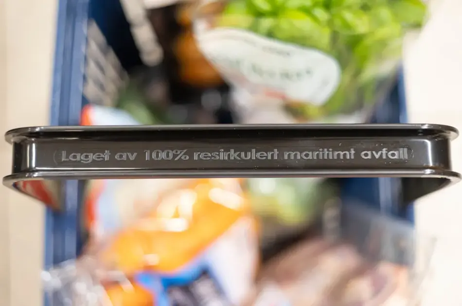 Handlekurv fra Rema 1000 med tekst på håndtaket "Laget av 100% resirkulert maritimt avfall"