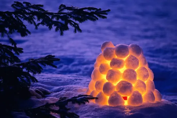 Snow lantern beside spruce tree in winter evening. Scanned from film.