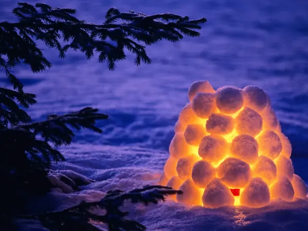 Snow lantern beside spruce tree in winter evening. Scanned from film.