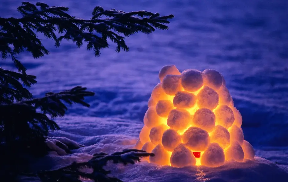 Snow lantern beside spruce tree in winter evening. Scanned from film.