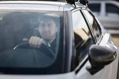 En mann som sitter i bilen og ser ut av vinduet 