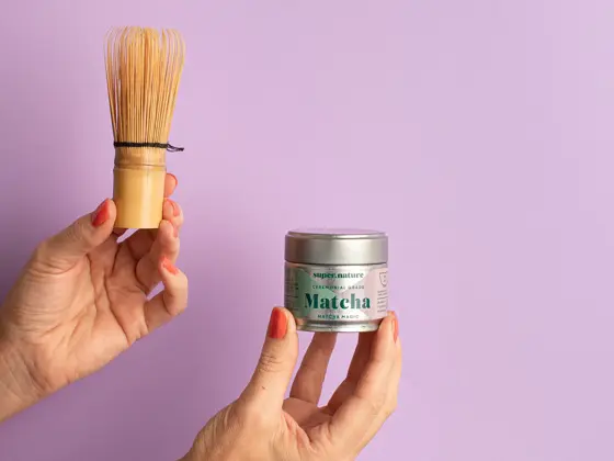 To hender osm holder pakke med matcha og en røreskje.