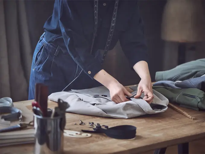 Dame som måler opp lengden på en skjorte