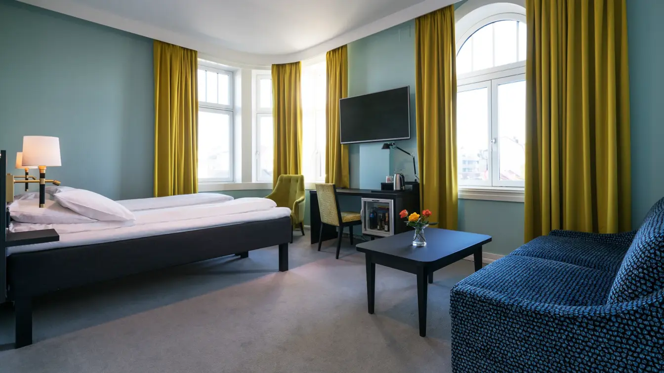 Seng, TV og sofa i familierom på Thon Hotel Nidaros