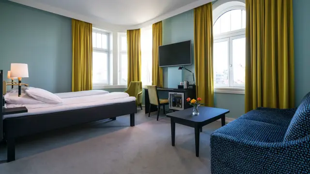 Seng, TV og sofa i familierom på Thon Hotel Nidaros